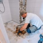 Close-up view of cracked shower floor tiles showing water damage and potential mold growth areas