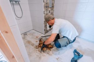 Close-up view of cracked shower floor tiles showing water damage and potential mold growth areas