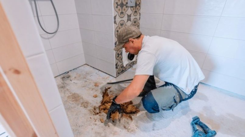Close-up view of cracked shower floor tiles showing water damage and potential mold growth areas