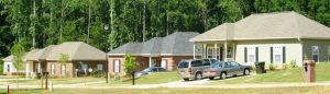 First-time home buyers standing in front of a new Alabama suburban house with mortgage approval documents