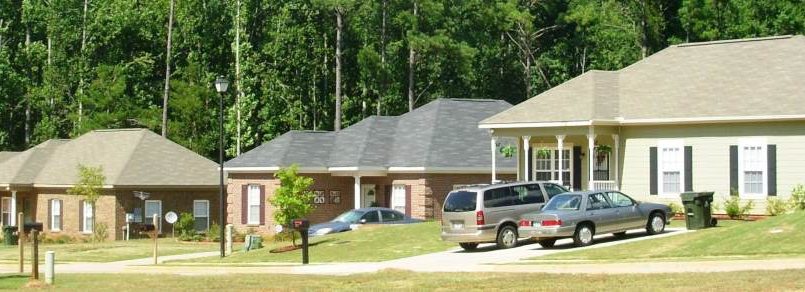 First-time home buyers standing in front of a new Alabama suburban house with mortgage approval documents