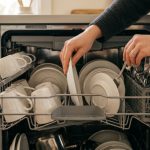 Person calculating utility bills next to a compact dishwasher.