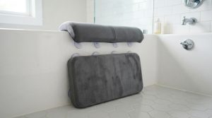 Thick memory foam bath kneeler pad with non-slip base beside a bathtub.