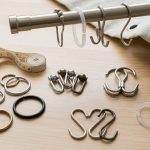 Roller shower curtain hooks gliding across a polished metal rod